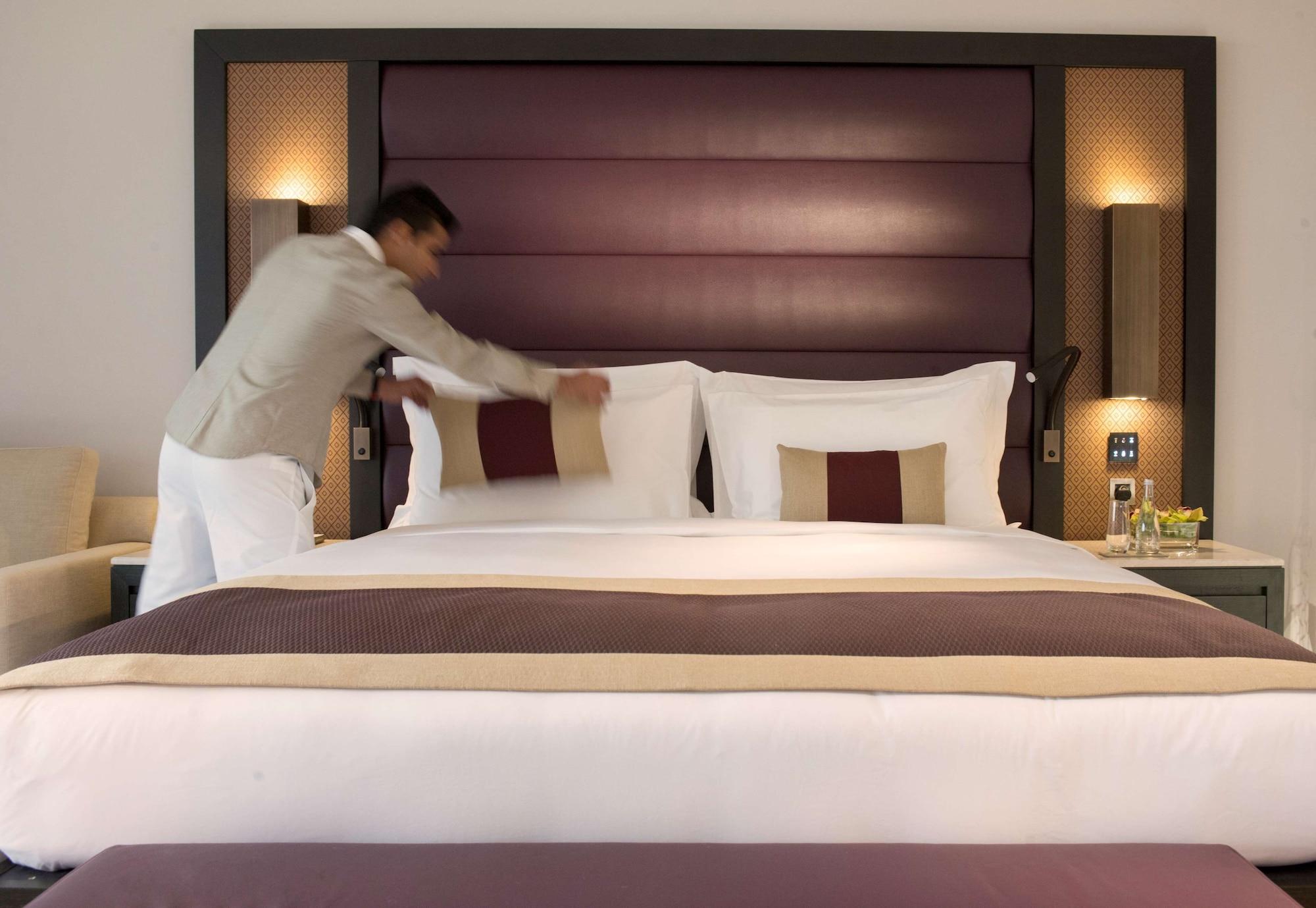 Kempinski Hotel Muscat Exterior photo A hotel housekeeper making a bed